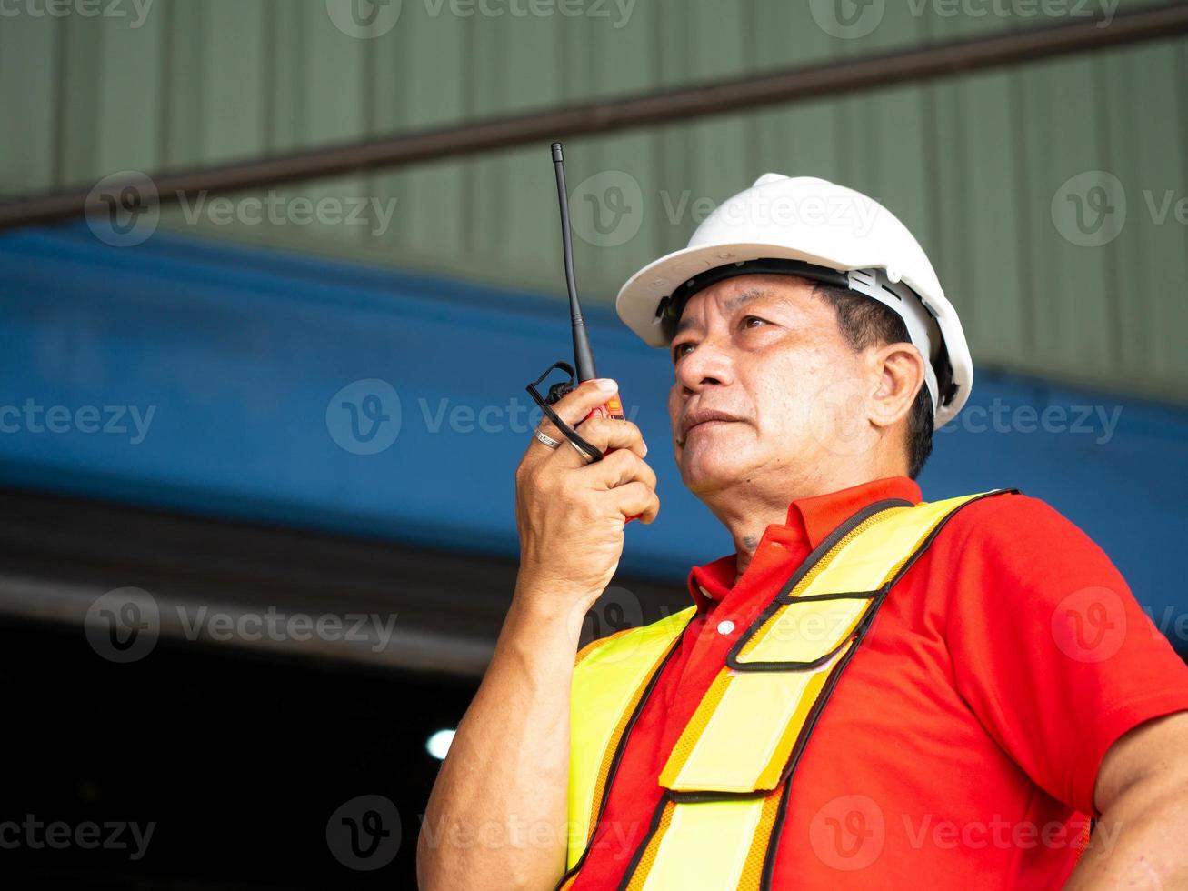 masculino pessoa Supervisor diretor fábrica companhia vestem branco capacete de segurança capacete segurança talkie walkie rádio homem ficar de pé ao controle trabalhos trabalho ocupação carreira ao controle logístico importar exportação carga construção foto