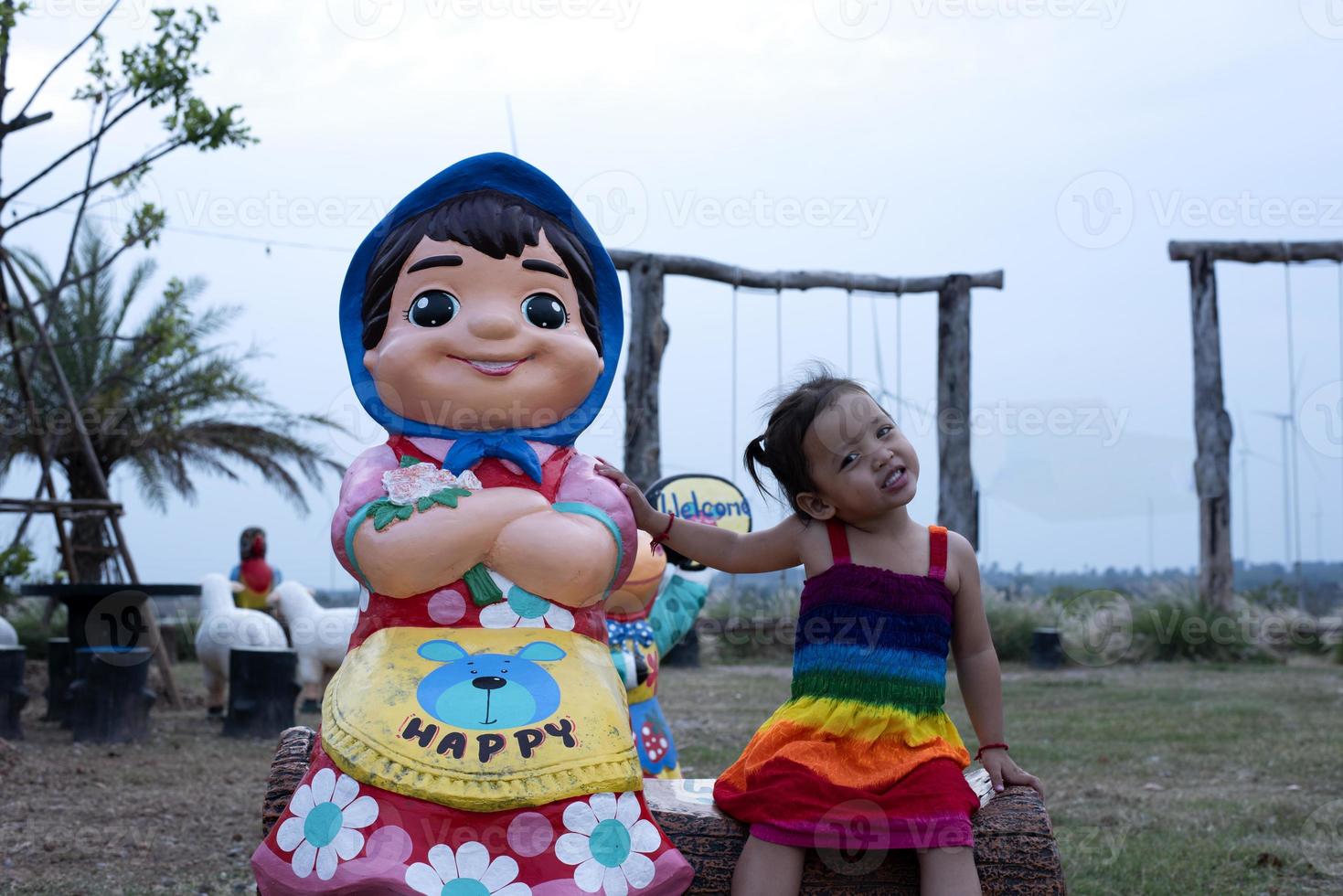 lindo jovem mãe filha senta e relaxar às verão Prado fundo e moinhos de vento, moinhos de vento Como alternativo energia fontes, sustentável recurso conceito, comunidade pessoas com moinhos de vento foto