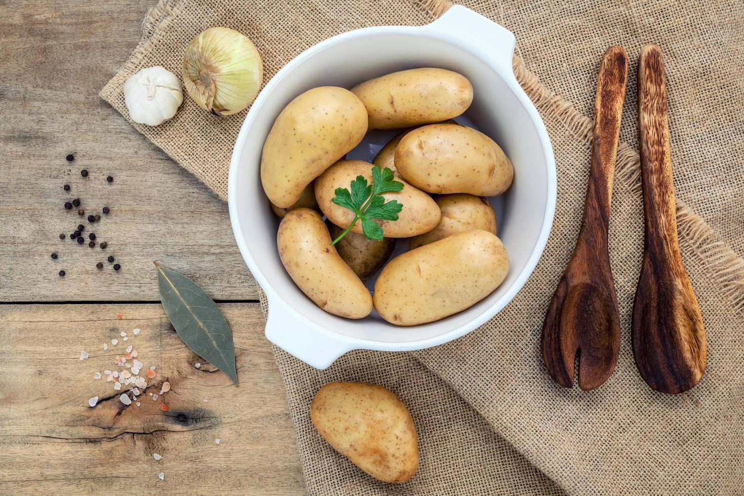 batatas frescas orgânicas em uma tigela de cerâmica branca com ervas foto