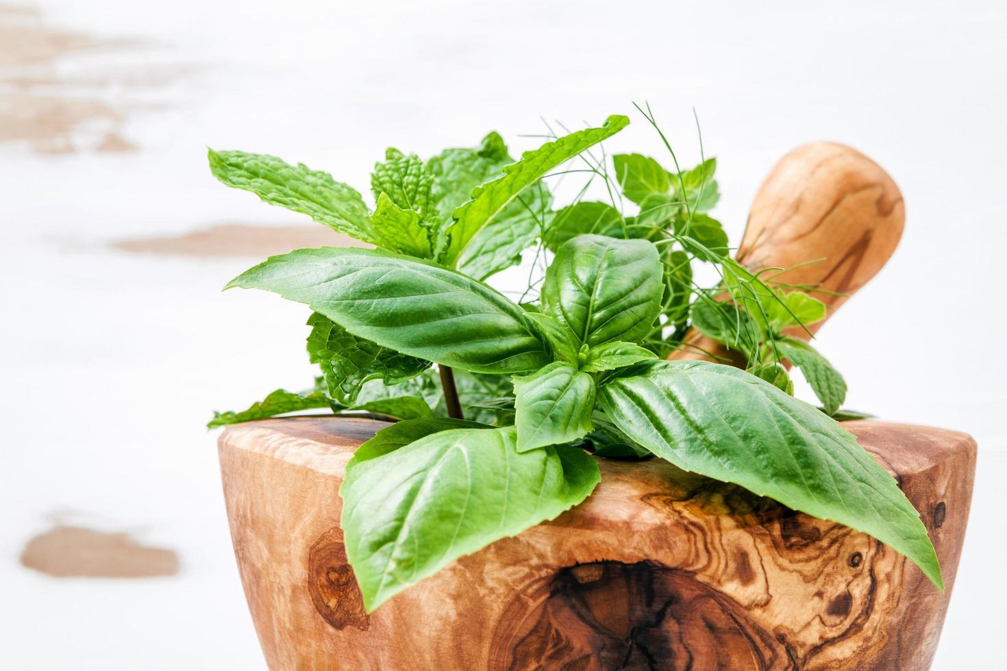 ervas verdes em um pilão de madeira foto