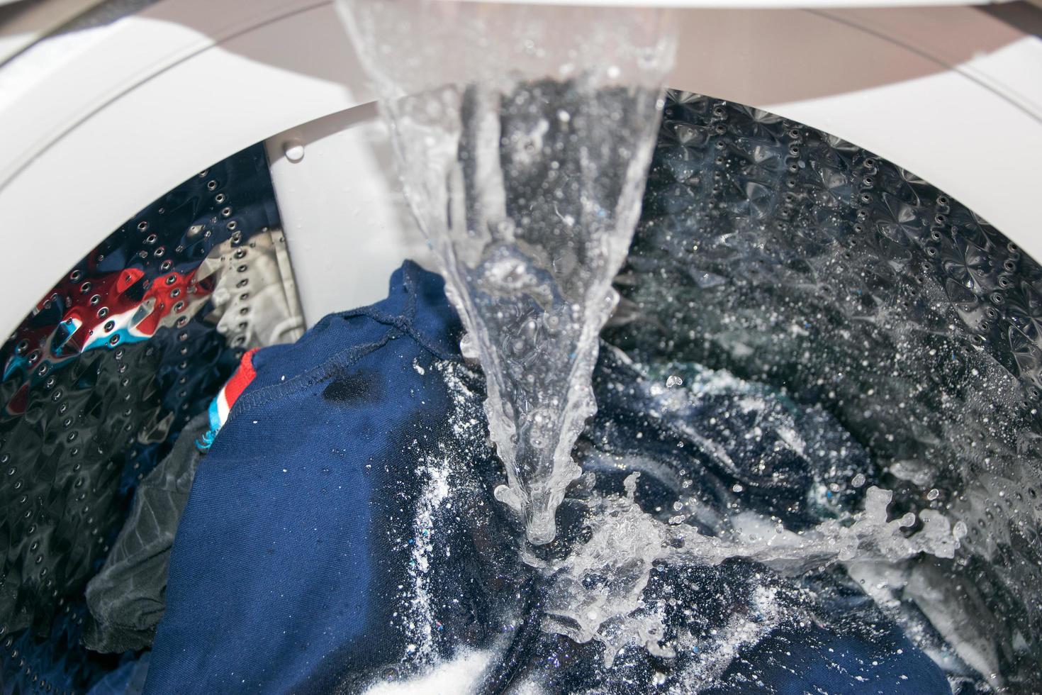 close-up de uma máquina de lavar jogando água nas roupas foto