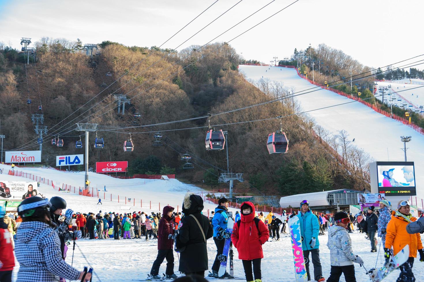 pessoas andando e brincando na neve com bondes do teleférico ao fundo no vivaldi park ski world na coréia foto