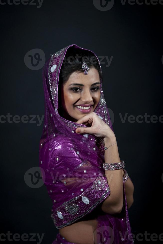 retrato do sorridente lindo indiano menina vestindo tradicional roxa roupas foto