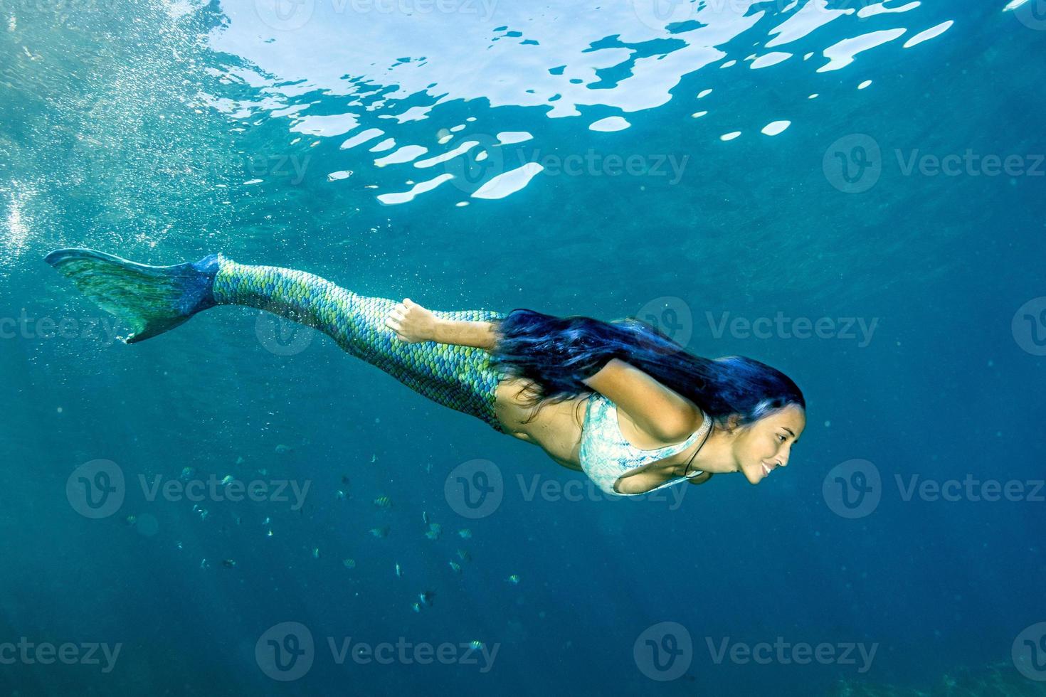 sereia nadando debaixo d'água no mar azul profundo foto