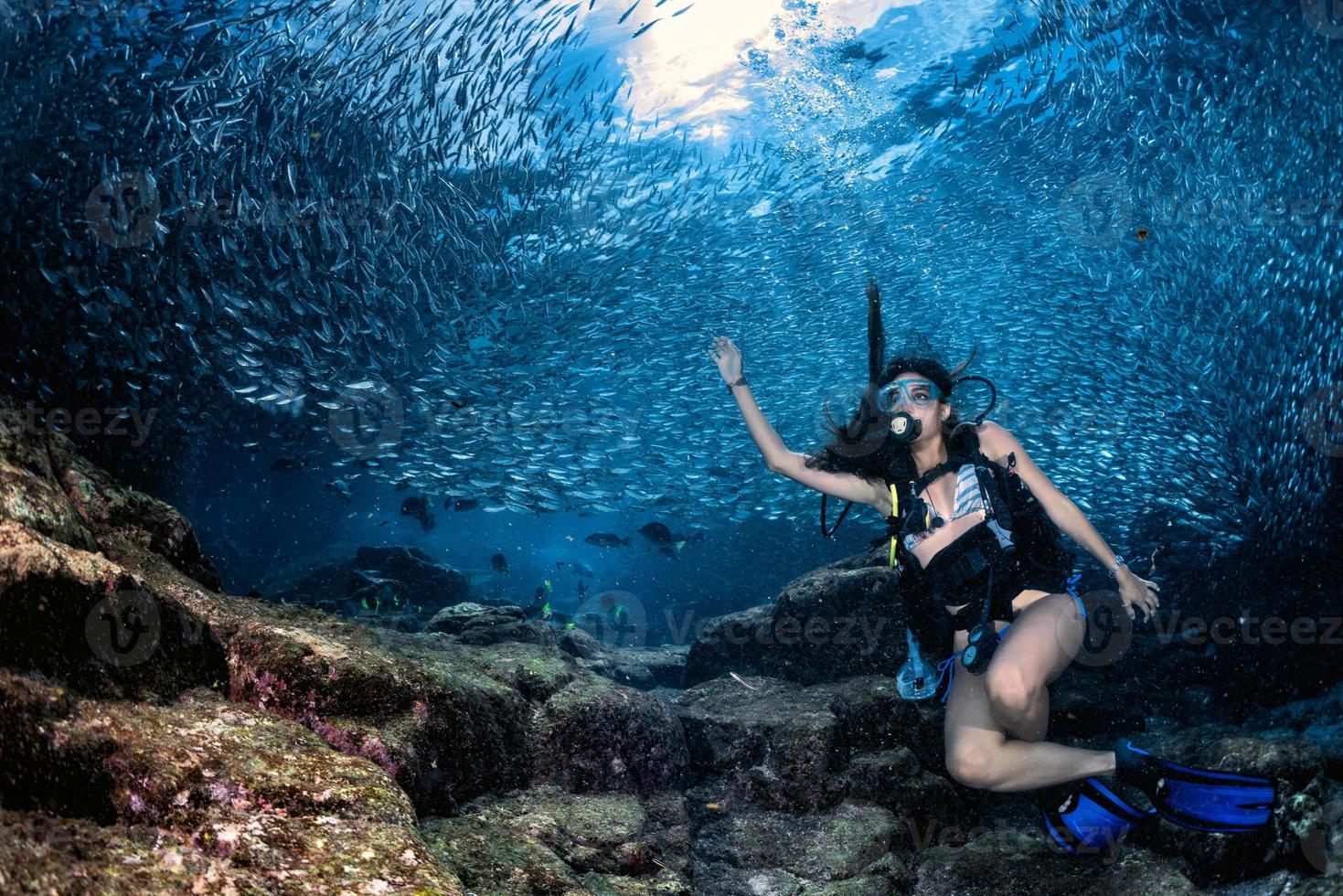 beaytiful latina mergulhador dentro de um cardume de peixes foto