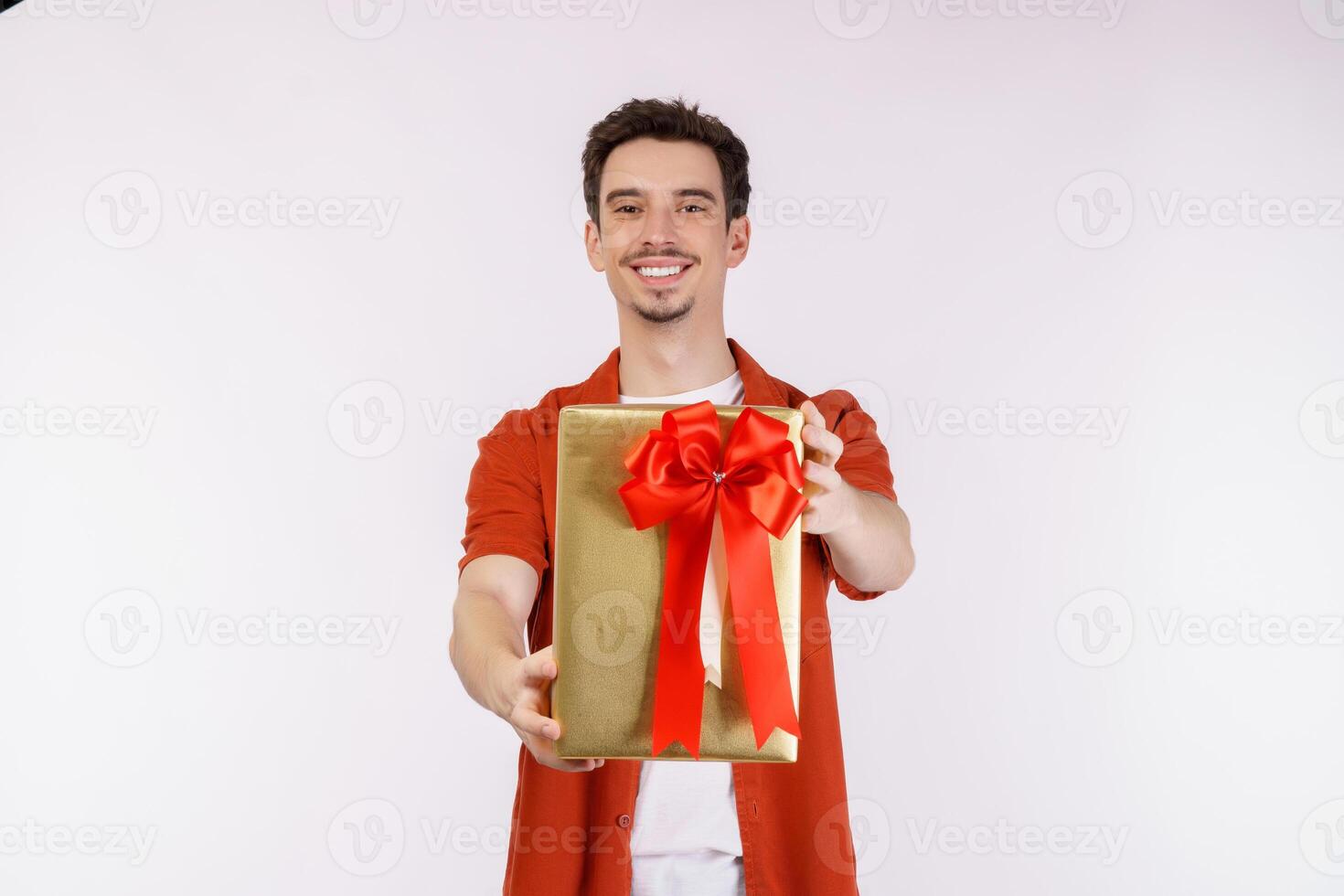 retrato de um jovem caucasiano feliz mostrando a caixa de presente e olhando para a câmera isolada sobre fundo branco foto