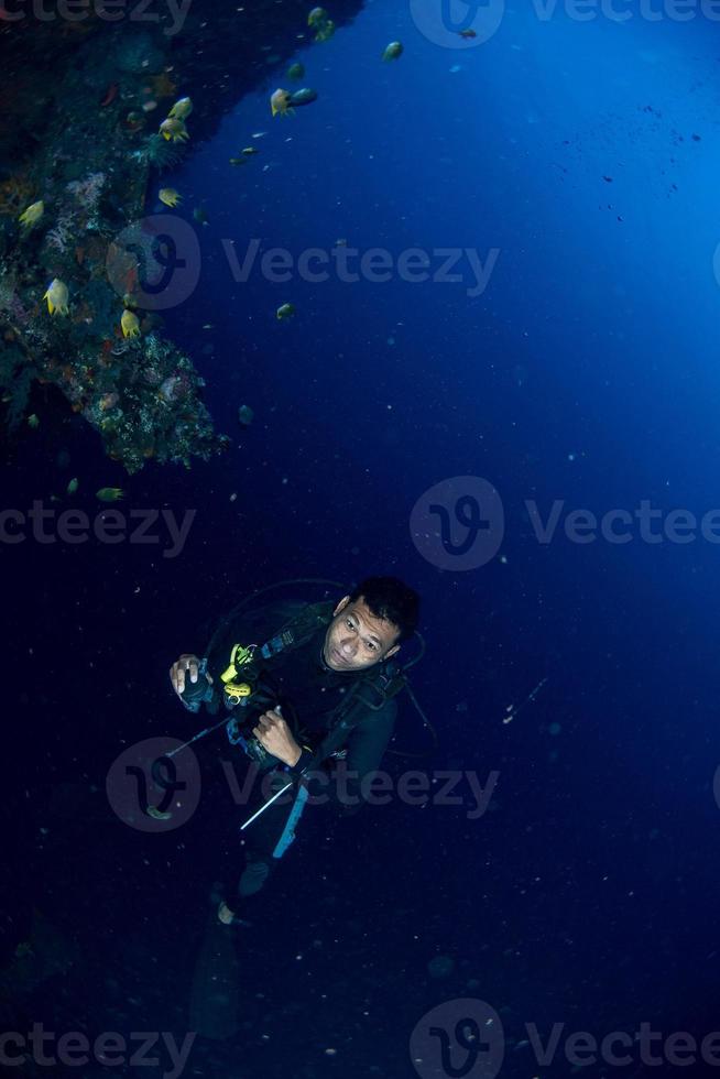 mergulhador debaixo d'água perto de peixes de pedra no oceano foto