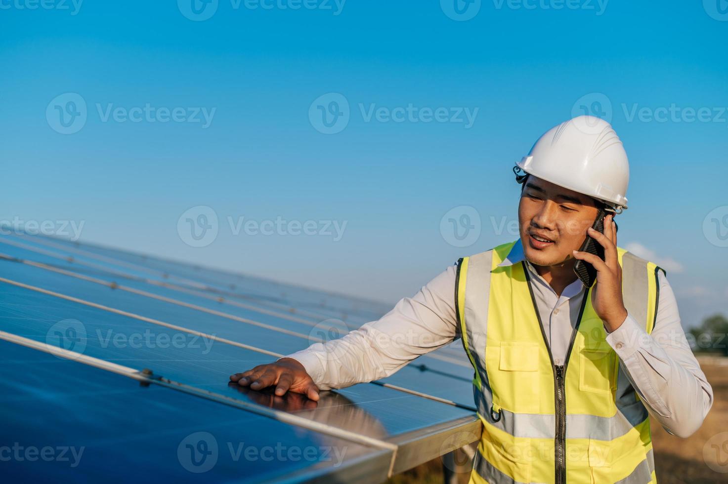 jovem engenheiro usa smartphone enquanto trabalha na fazenda solar foto