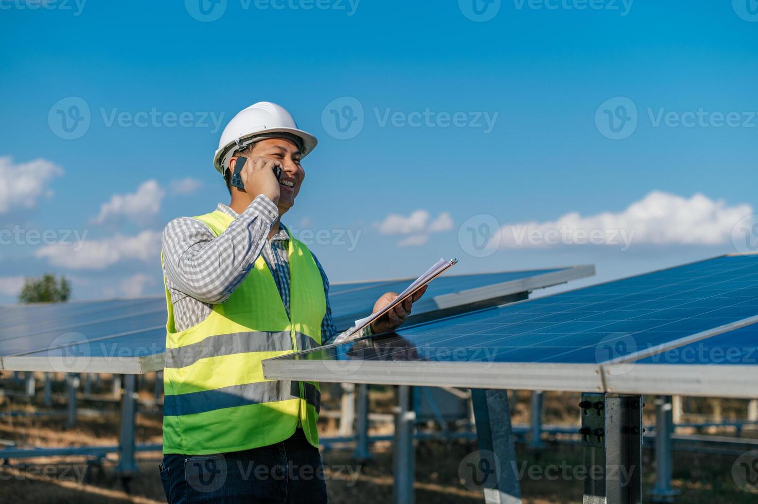 jovem engenheiro falando no smartphone enquanto trabalhava na fazenda solar foto