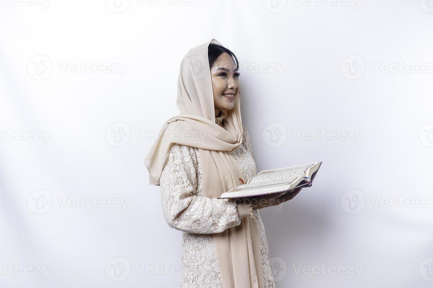 jovem mulher muçulmana asiática sorrindo e segurando o Alcorão foto