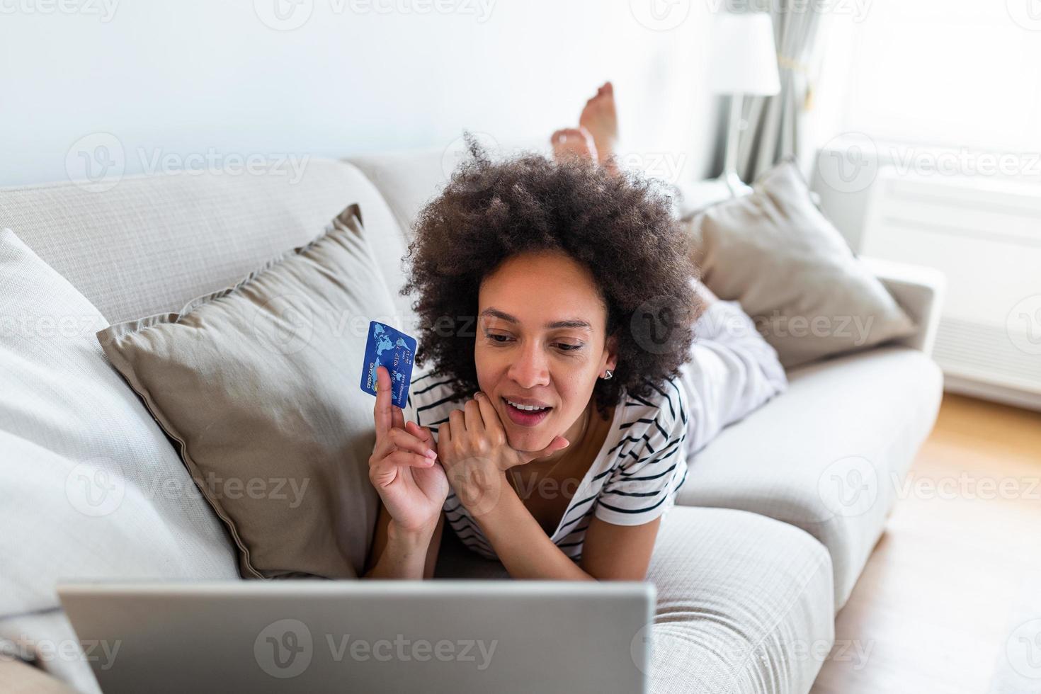 Internet pagamento. feliz alegre mulher olhando às a Internet tela enquanto fazer a Internet pagamento. feliz jovem mulher com crédito cartão e computador portátil sentado em sofá às lar. conectados Forma de pagamento foto