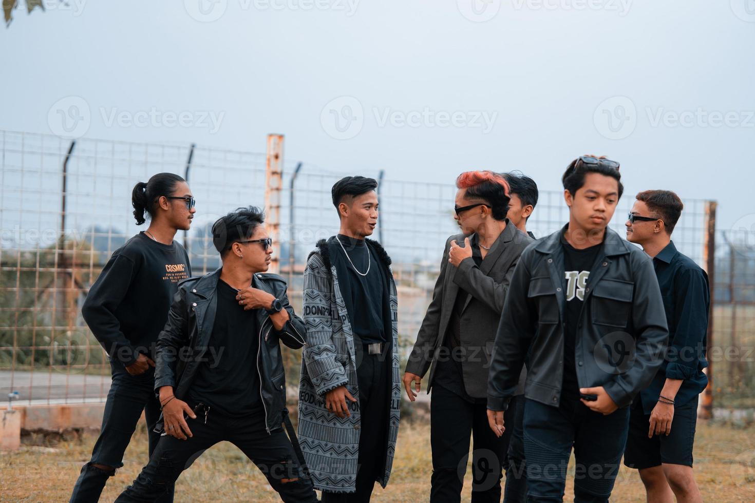 uma grupo do Adolescência Rapazes dentro Preto roupas posando muito galantemente com seus amigos dentro uma campo foto