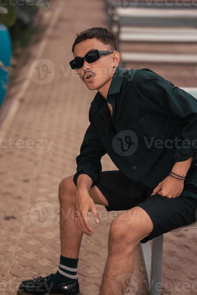 a ásia homem com uma bigode face vestindo uma camisa e oculos de sol dentro uma muito masculino estilo foto