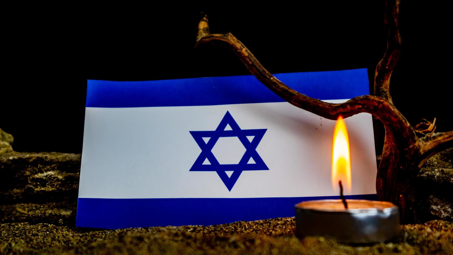 bandeira israelense e velas queimando na frente dela, dia da memória do holocausto foto