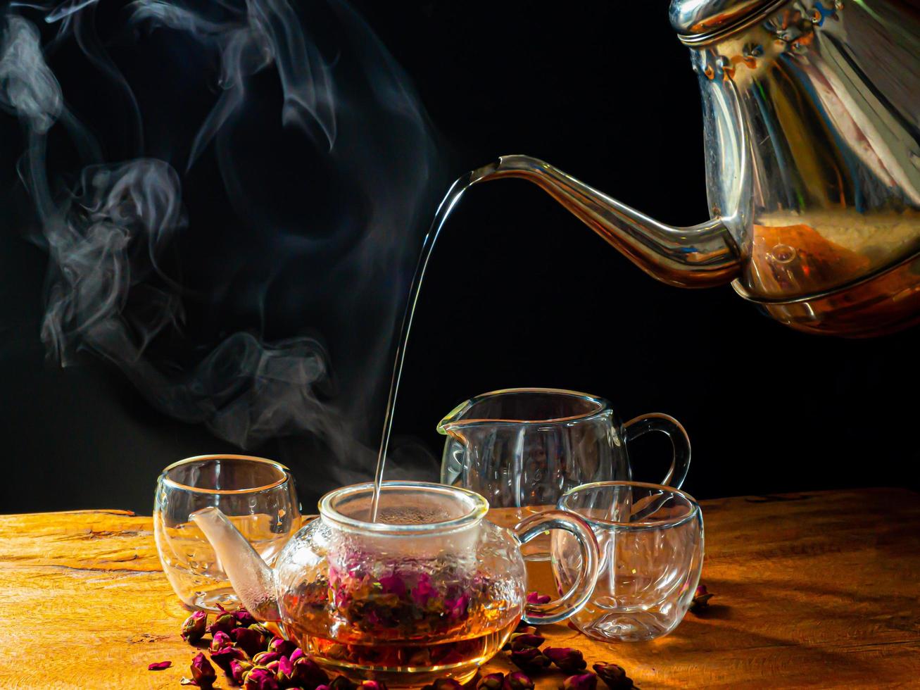 folhas de chá de rosas em uma caneca de vidro e bule de chá foto