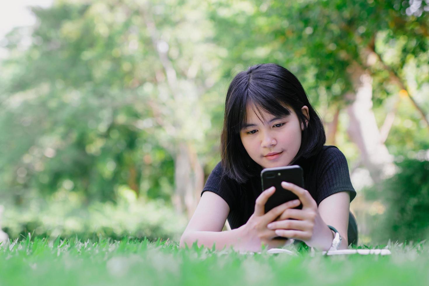 uma menina sentada no jardim com seu telefone foto