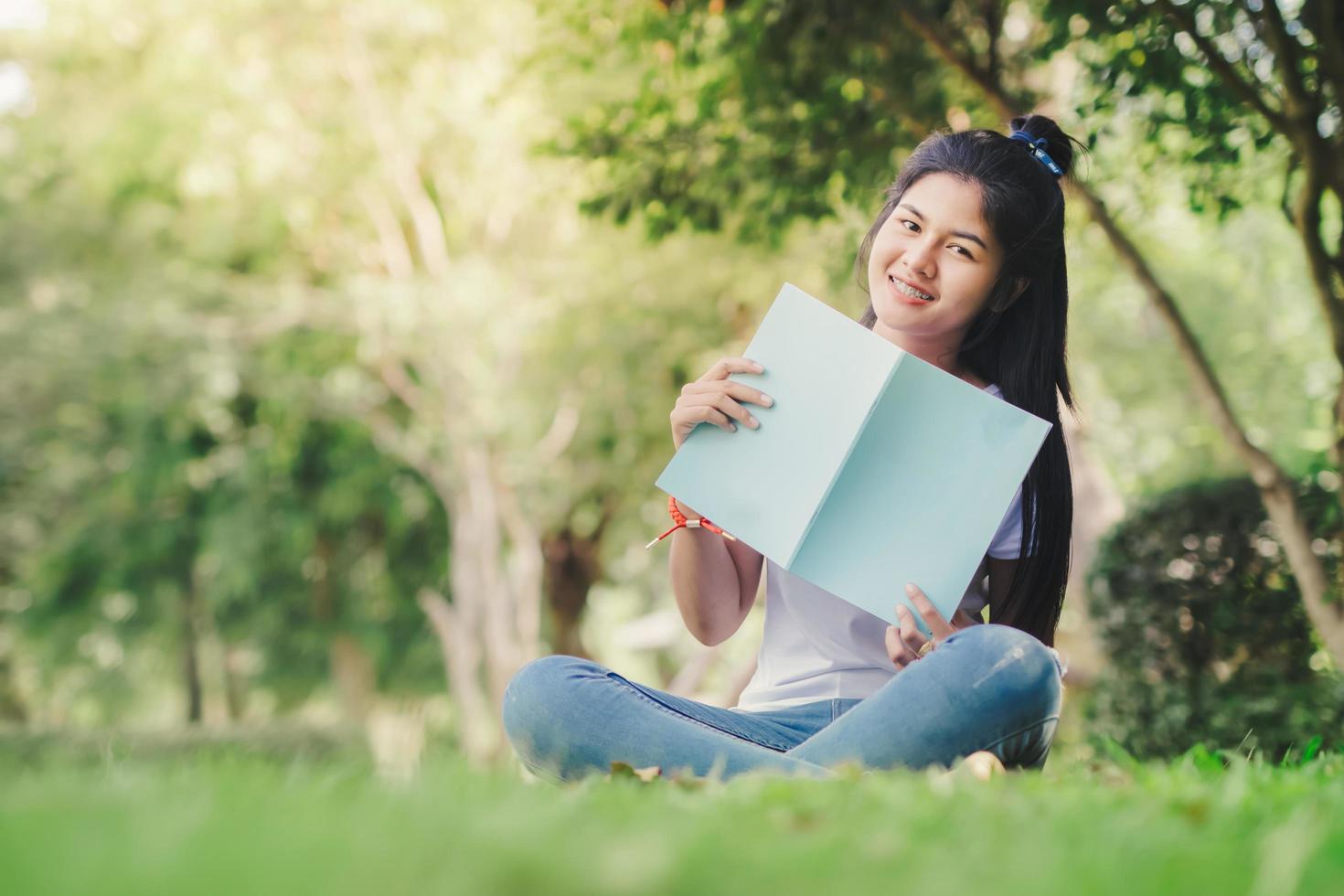 uma mulher sentada e lendo um livro no jardim foto