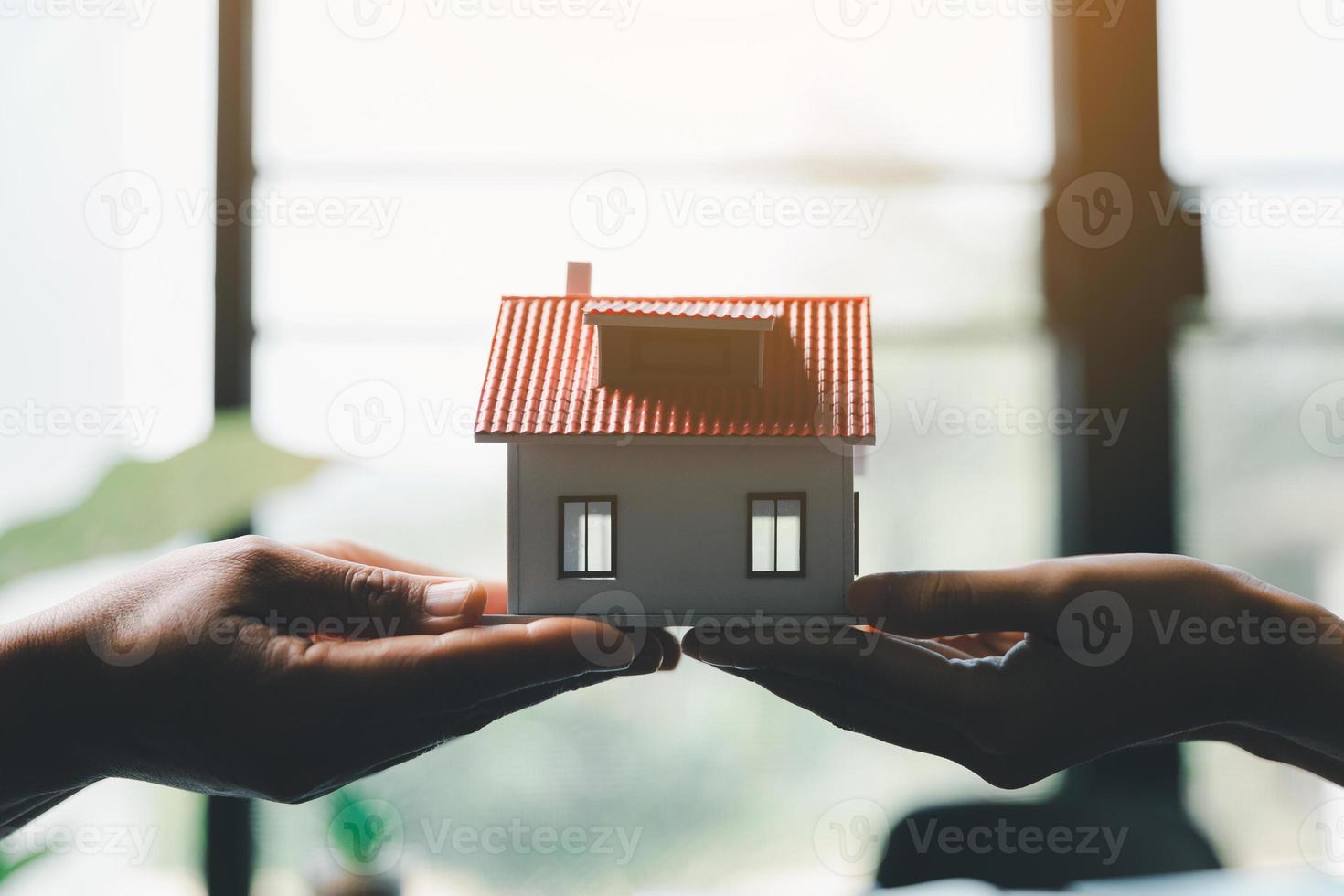 o negócio mulher segurando casa miniatura dentro escritório escritório. seguro protetora mão sobre casa para proteção e Cuidado, conceito do casa e real Estado propriedade seguro. foto