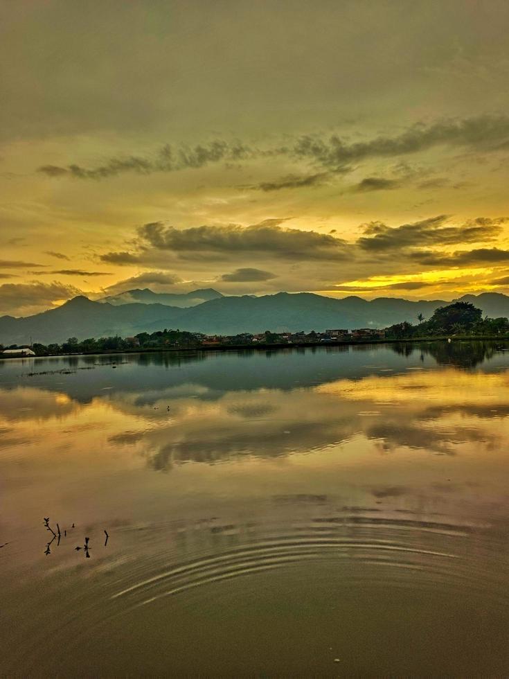 uma lago com uma montanha em pé atrás isto debaixo a tarde nuvens foto