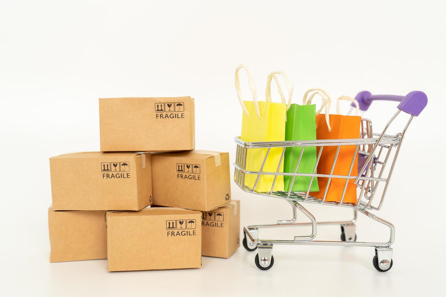 caixas de papel e sacolas de compras em um carrinho em um fundo branco. conceito de compras online ou e-commerce e conceito de serviço de entrega foto