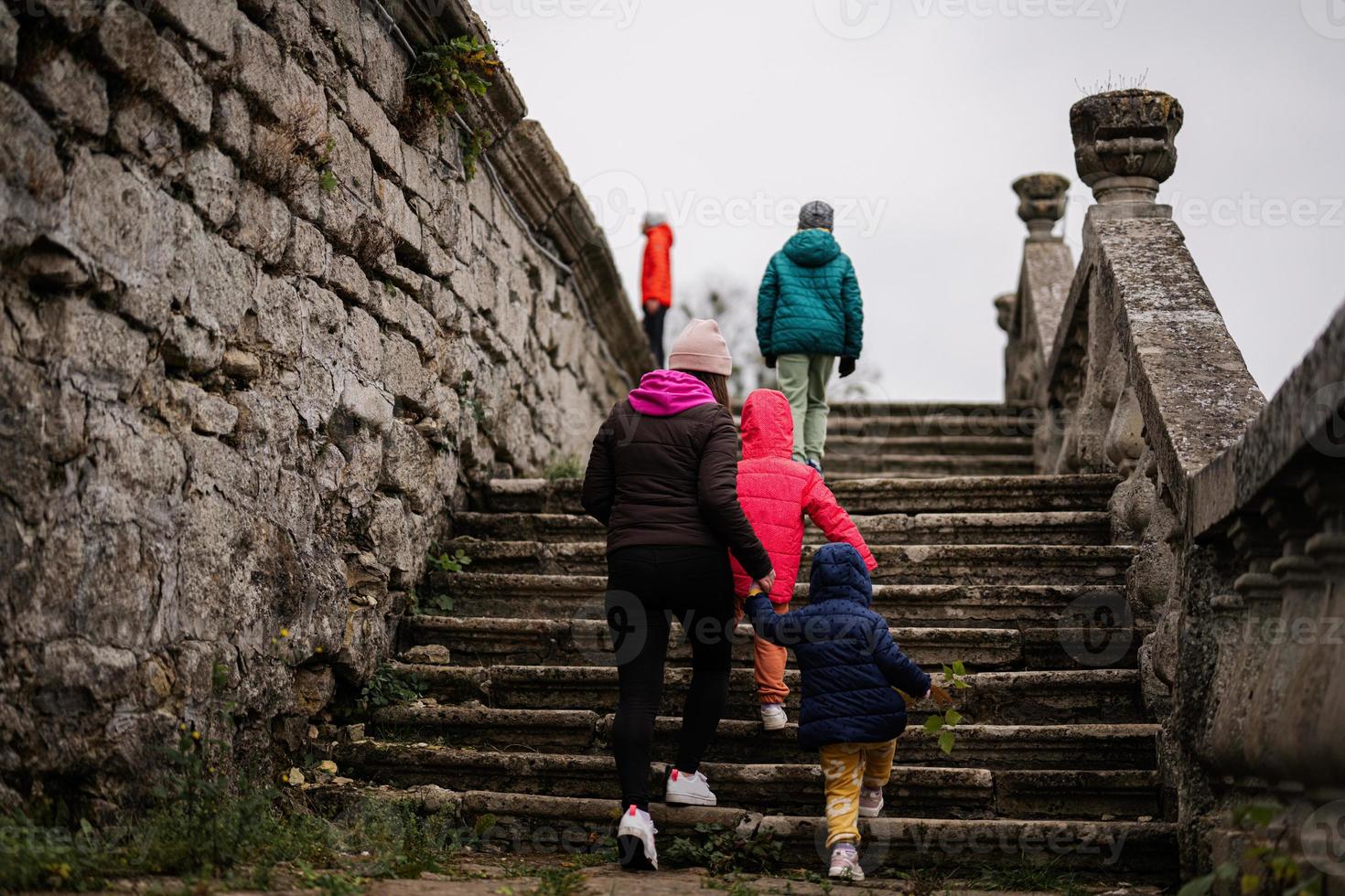 mãe com quatro filhos andando nas escadas do castelo pidhirtsi, região de lviv, ucrânia. turista familiar. foto