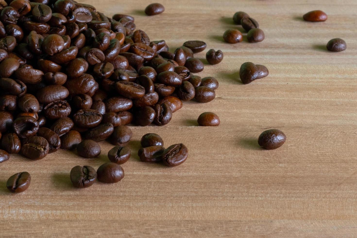 grãos de café torrados em fundo de madeira foto