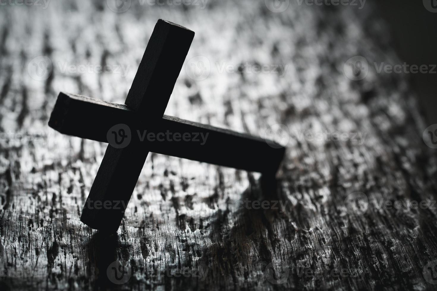 uma de madeira cristão Cruz crucifixo em uma grunge borda fundo. de madeira cristão Cruz em cinzento mesa contra borrado luzes, espaço para texto. foto