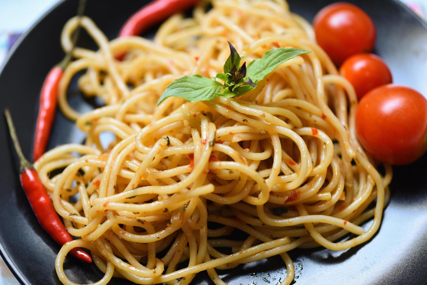 espaguete massa e tomate Pimenta e manjericão folhas legumes - tradicional delicioso italiano Comida espaguete bolonhesa em prato em a jantar mesa foto