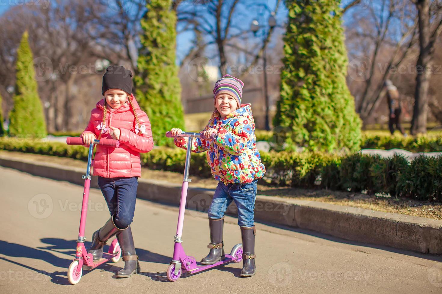 pequeno irmãs equitação patinetes ao ar livre foto