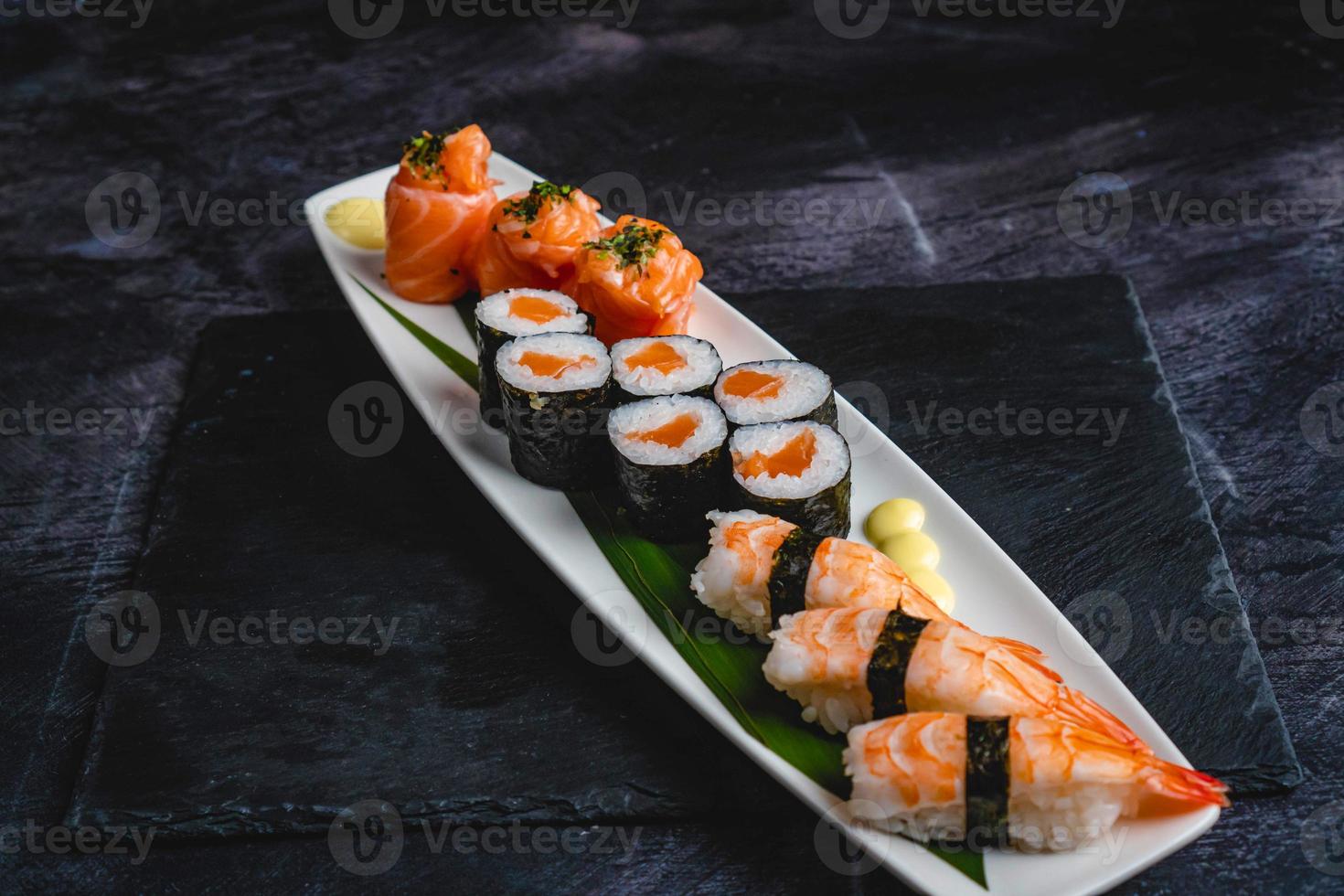uma branco prato coberto com Sushi em topo do uma Preto mesa, torcido formas, três torres, grandes fluindo barbatanas. foto
