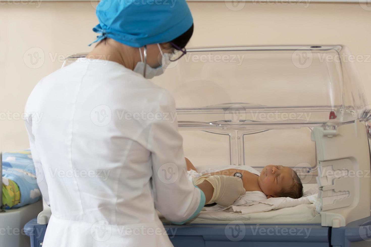 neonatologia. médico ouvindo para a batimento cardiaco do uma recém-nascido dentro a infantil incubadora foto