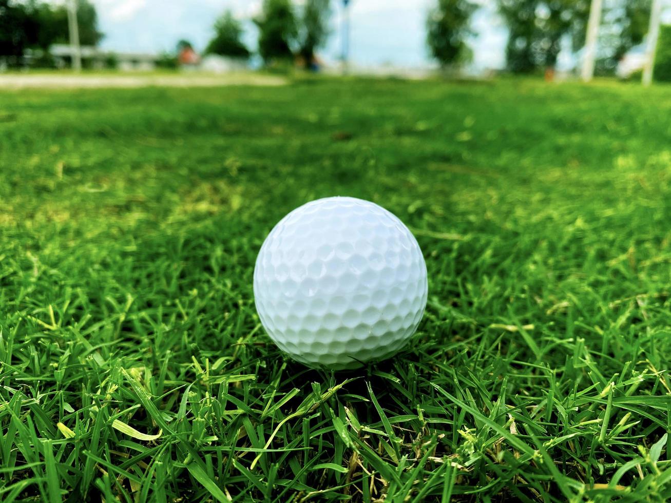 bola de golfe fechar na grama verde na bela paisagem borrada do campo de golfe com nascer do sol, hora do pôr do sol no esporte internacional background.concept que dependem de habilidades de precisão para relaxamento de saúde. foto