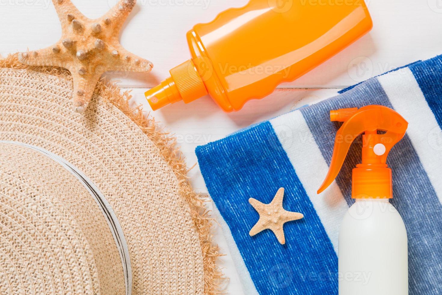 frascos de protetor solar com estrela do mar e chapéu de sol na mesa de madeira branca com espaço de cópia. vista superior de acessórios de saúde de viagem foto