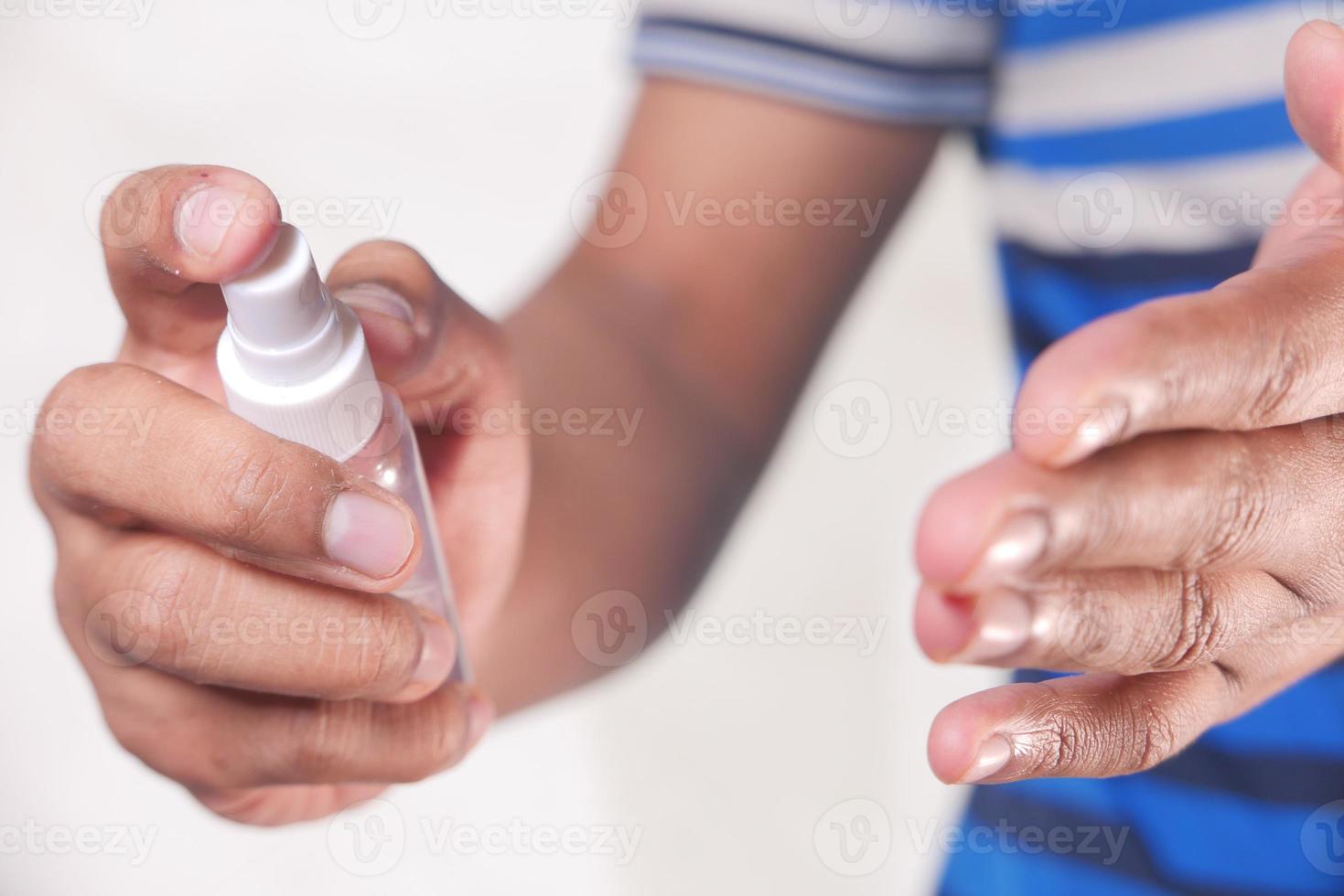 mão de jovem usando spray desinfetante para as mãos foto