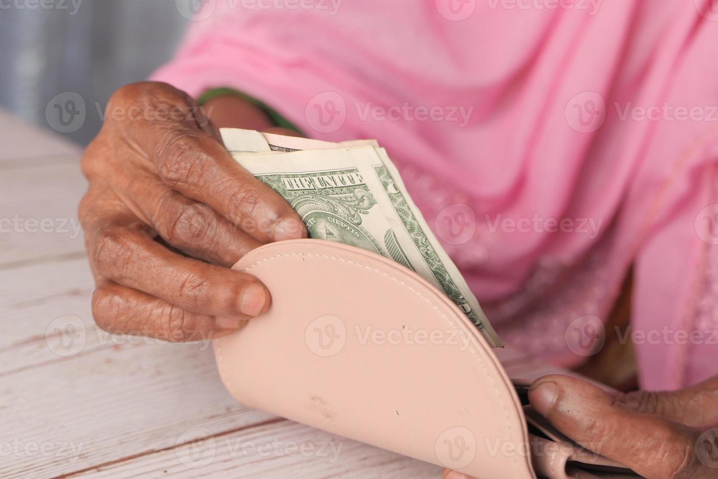close-up de pessoa economizando dinheiro na carteira foto