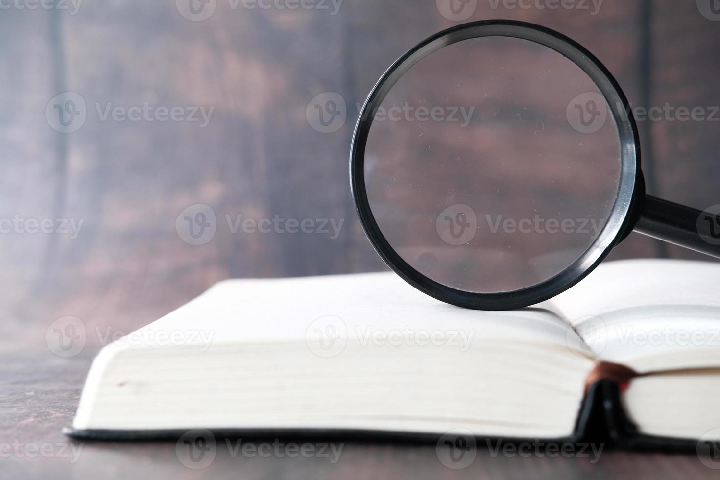 livro aberto e lupa na mesa foto