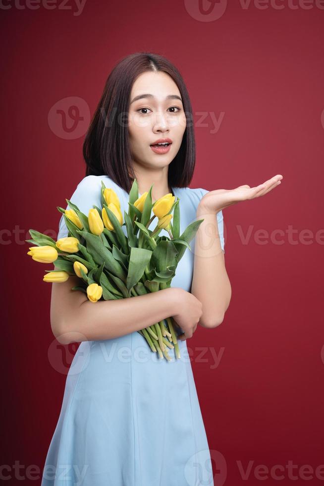 imagem do jovem ásia mulher segurando tulipas flores em fundo foto