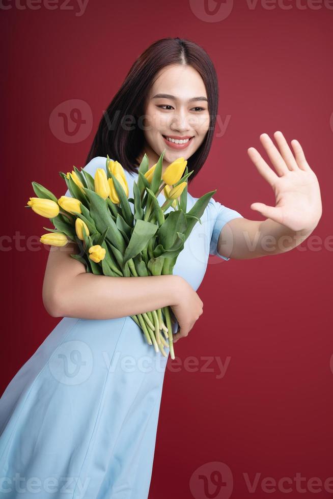 imagem do jovem ásia mulher segurando tulipas flores em fundo foto