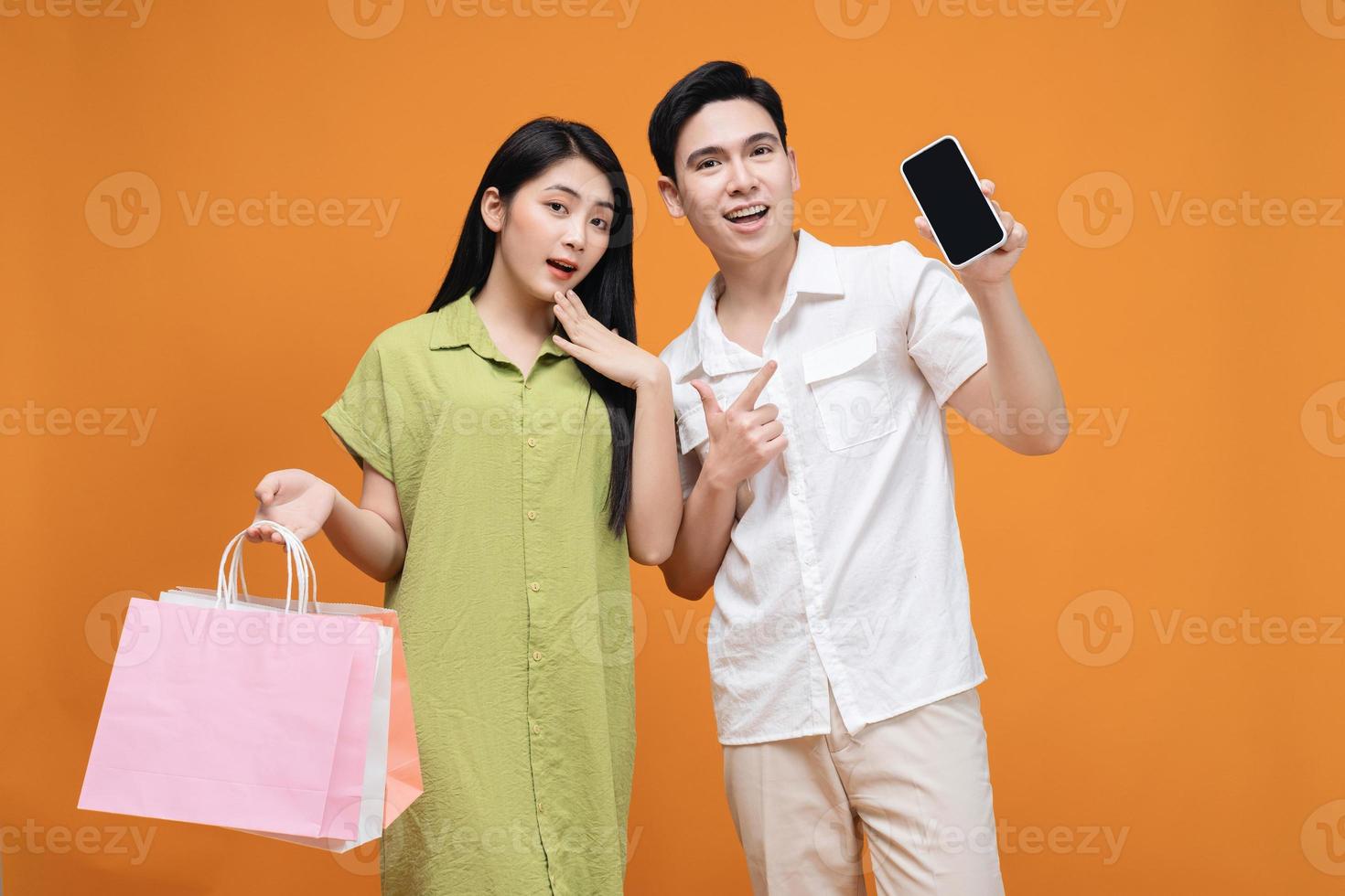 jovem ásia casal segurando compras saco em fundo foto