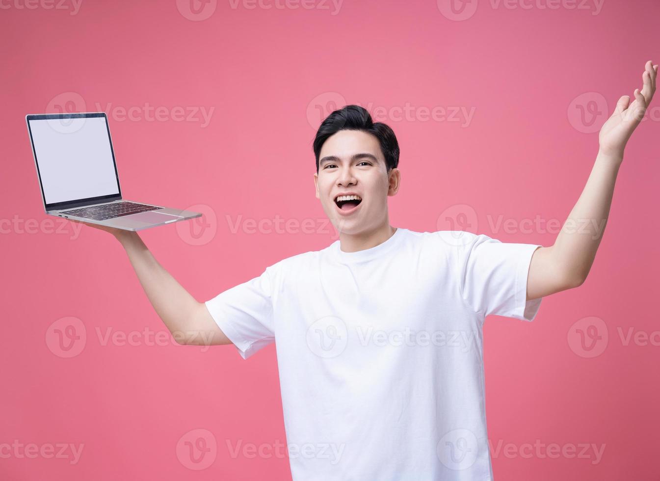 jovem ásia homem segurando computador portátil em fundo foto