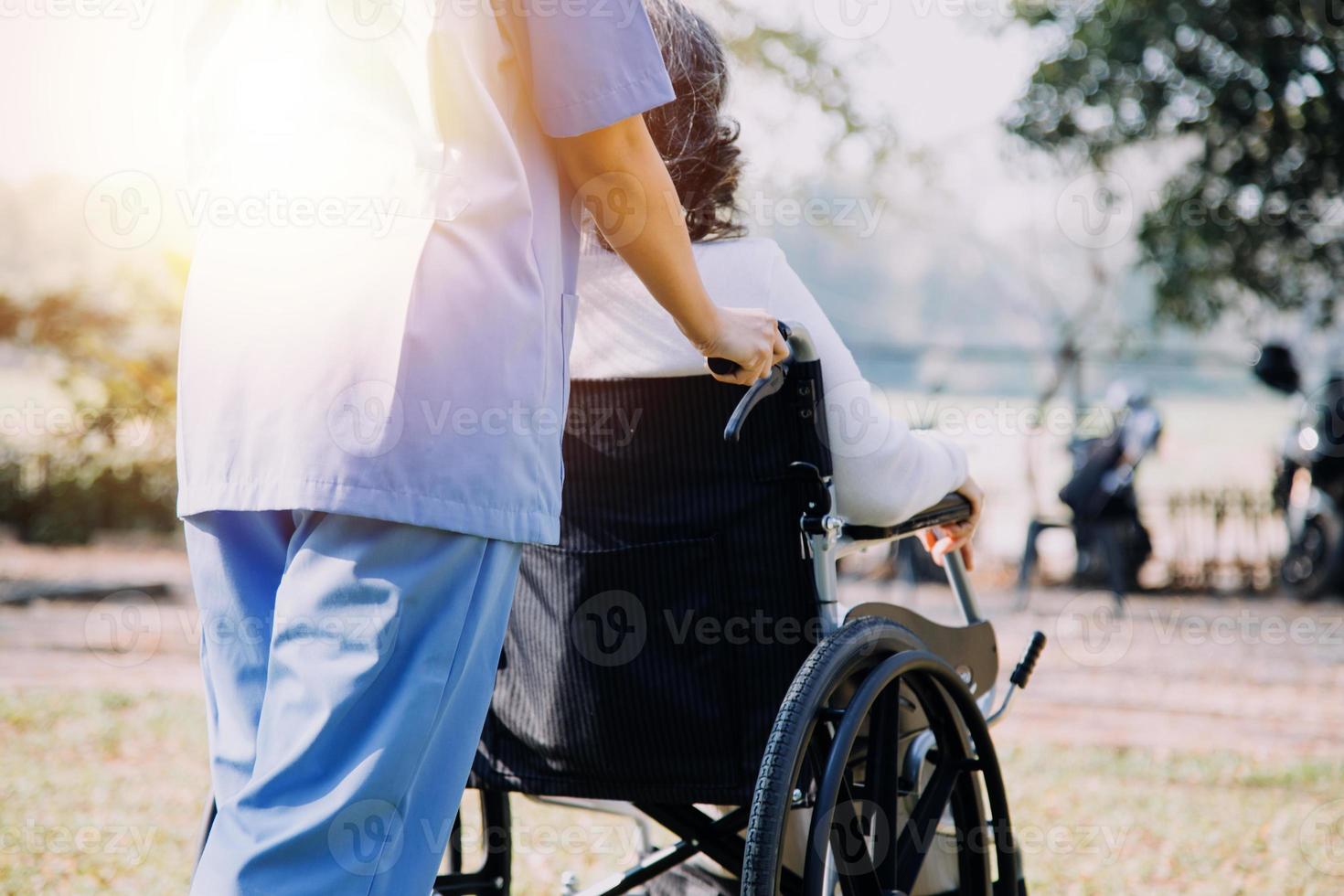 ásia jovem cuidador enfermeira Apoio, suporte Senior Mais velho masculino caminhando ao ar livre. especialista menina médico Socorro e levar Cuidado do idosos maduro homem paciente fazendo fisica terapia dentro público parque às enfermagem lar. foto