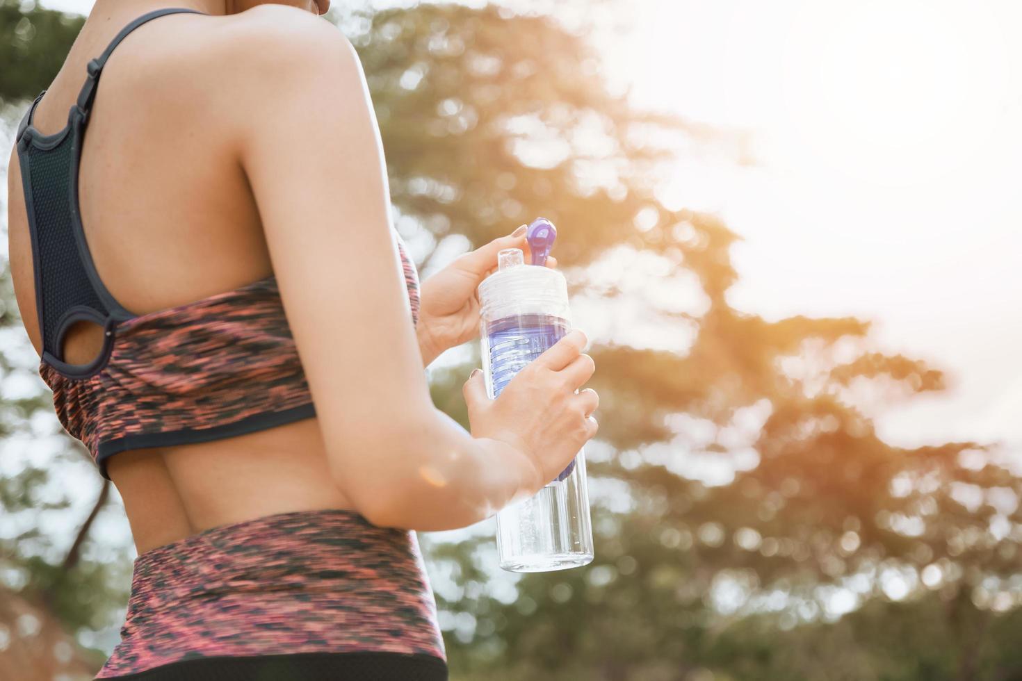uma corredora em pé ao ar livre segurando uma garrafa de água, conceito saudável e esporte foto