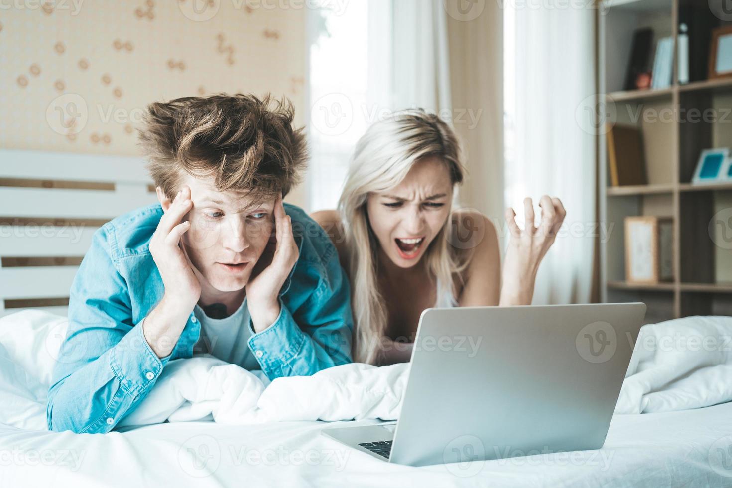 casal feliz usando laptop na cama foto