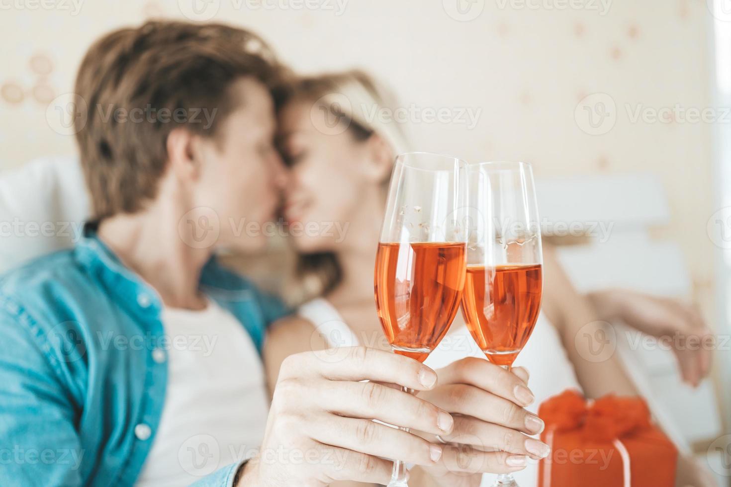 casal feliz bebendo vinho no quarto foto