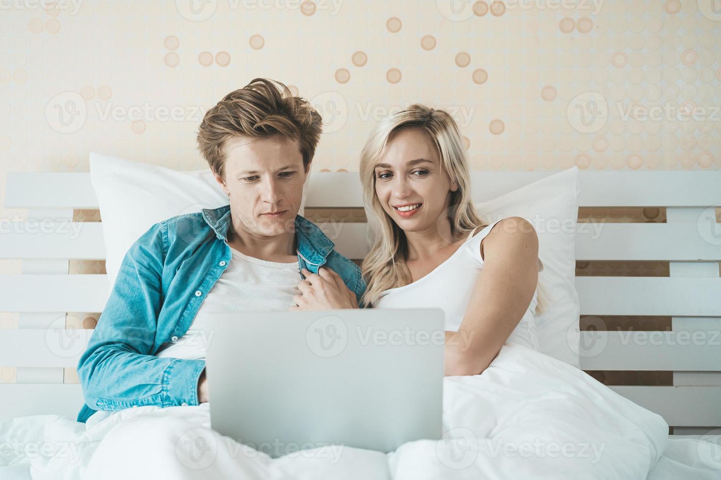 casal feliz usando laptop na cama foto