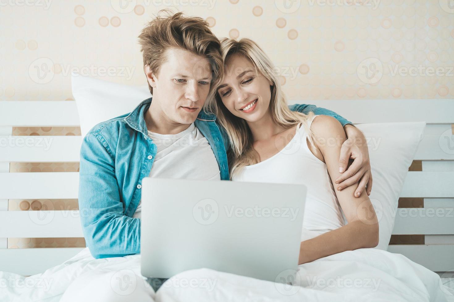 casal feliz usando laptop na cama foto