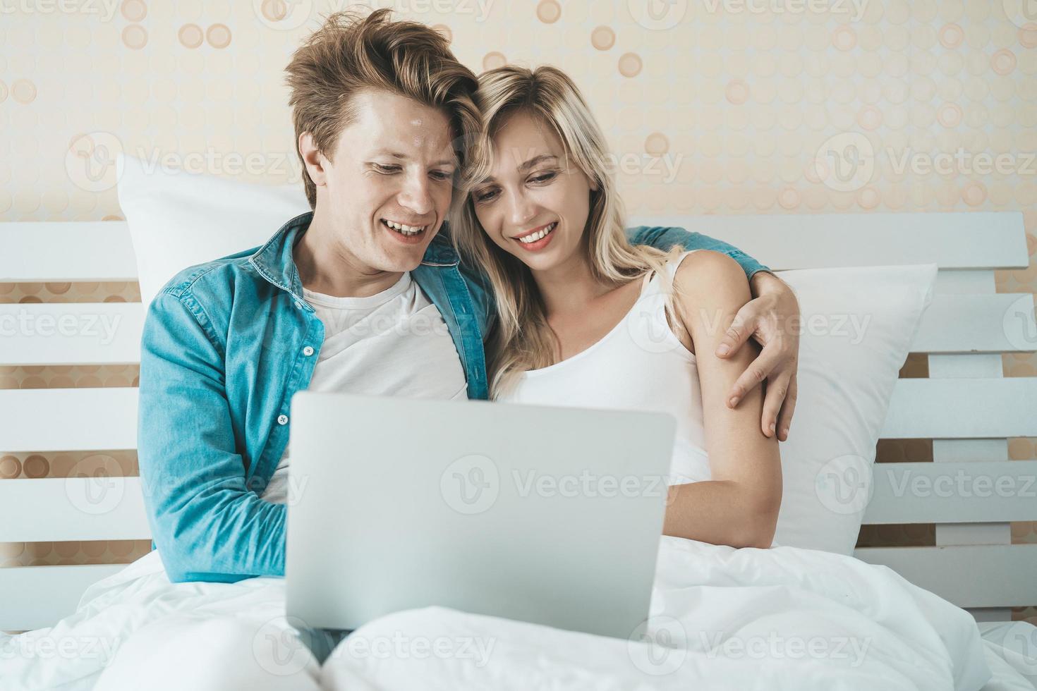 casal feliz usando laptop na cama foto