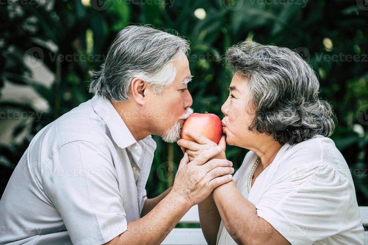 casal de idosos brincando e comendo frutas foto