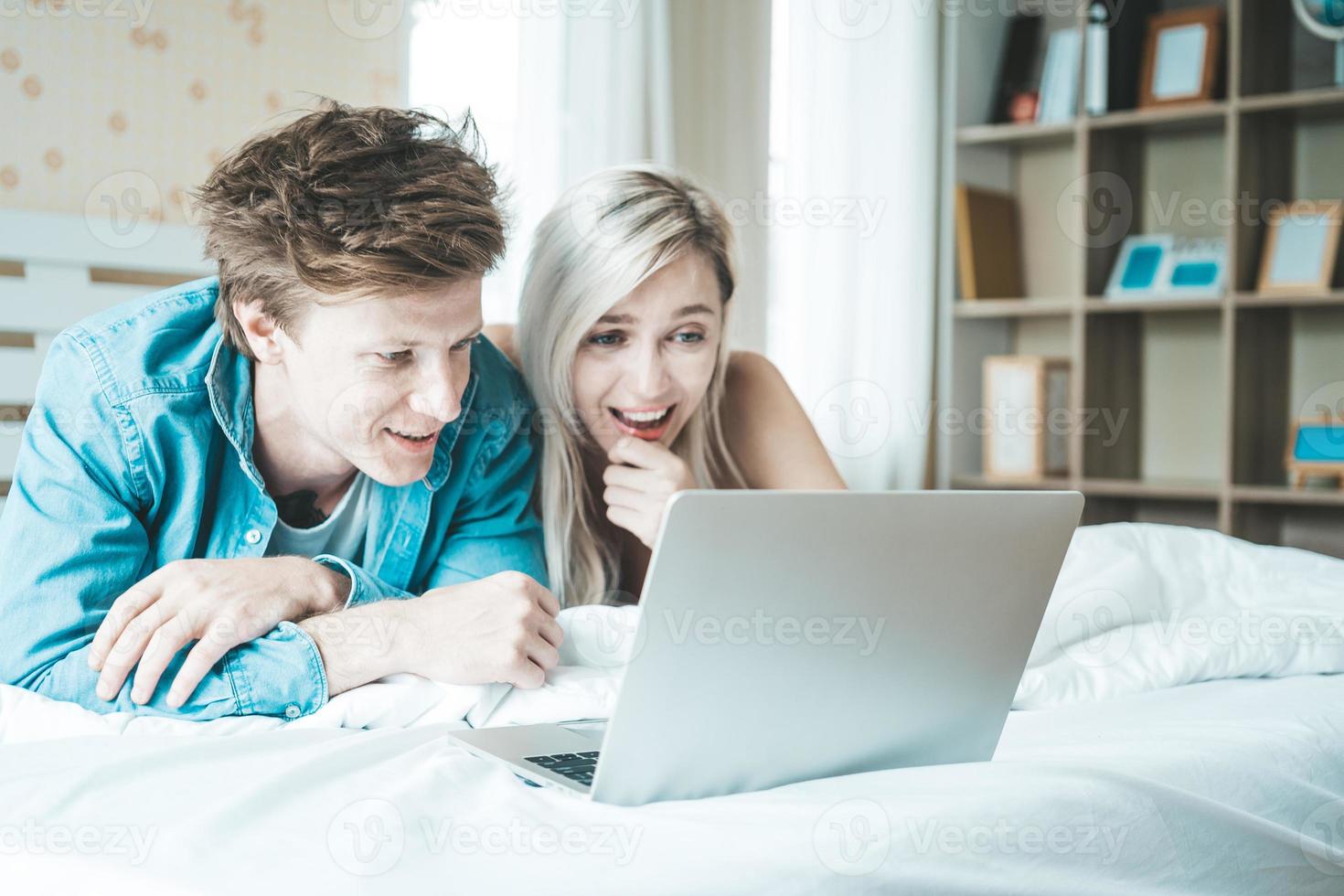 casal feliz usando laptop na cama foto