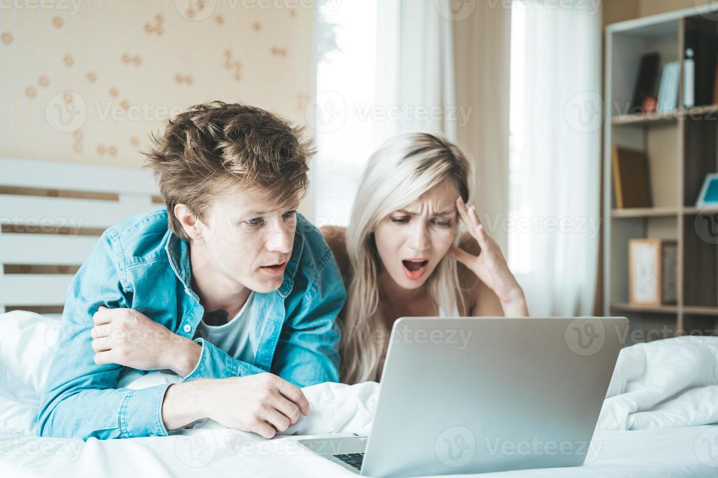 casal feliz usando laptop na cama foto